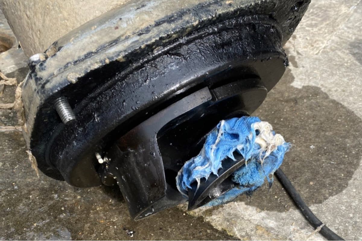 Submersible sewage pump pulled for inspection, impeller wrapped in wet wipes and rag matter, the dominant clogging failure mode in collection networks.